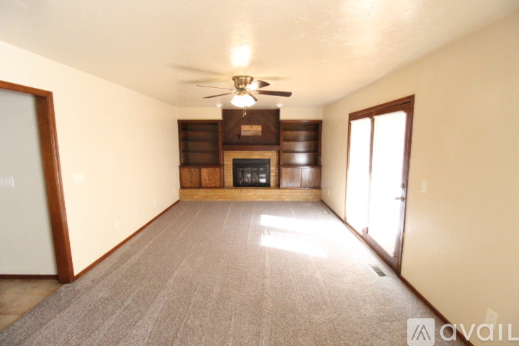 A spacious living room with a ceiling fan and a fireplace.