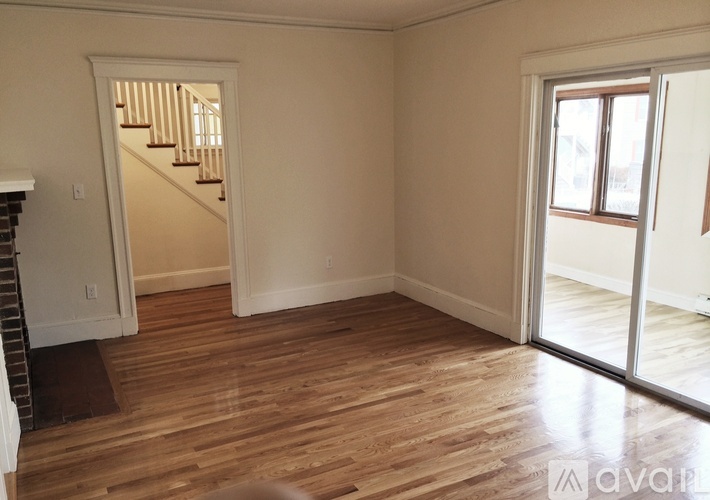 A room with wooden floors and a staircase leading to another room.