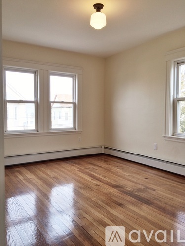 A room with wooden floors and two windows.