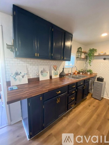 A kitchen with black cabinets and a wooden countertop.