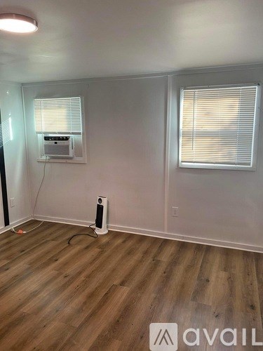 A room with wooden flooring and a window with blinds.