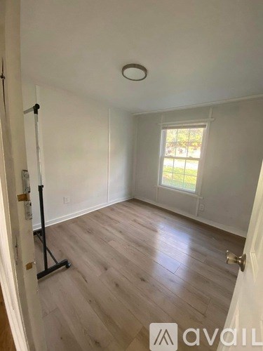 A room with wooden flooring and a window letting in natural light.