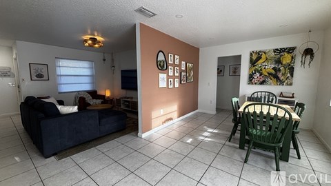 A living room with a couch, a dining table and chairs, and pictures on the wall.