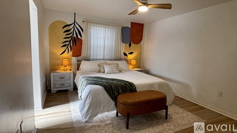 A bedroom with a bed, a bench, and a fan.