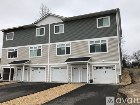 A two-story house with a grey facade and white garage doors.