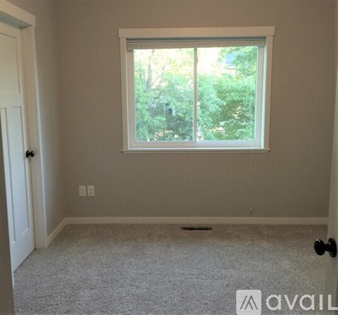 A room with a window and a carpeted floor.