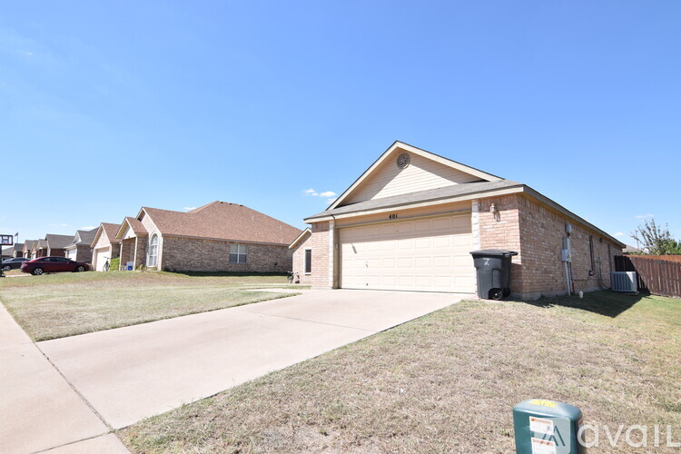 A house with a driveway and a trash can in front.