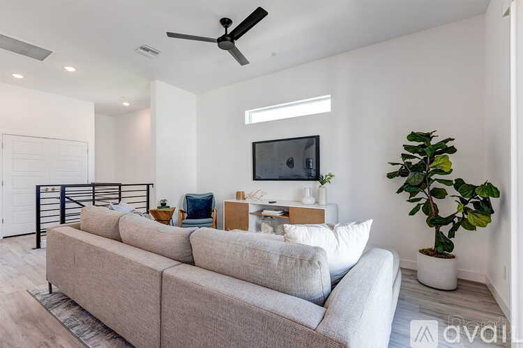 A living room with a grey sofa and a television on the wall.