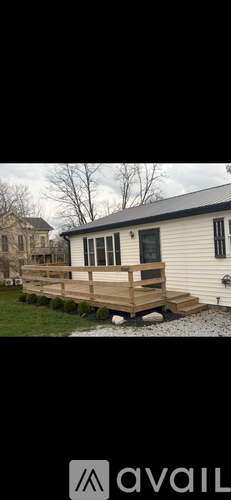 A house with a wooden deck and a gravel path leading to it.