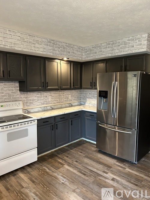A kitchen with a white stove top oven and a stainless steel refrigerator.
