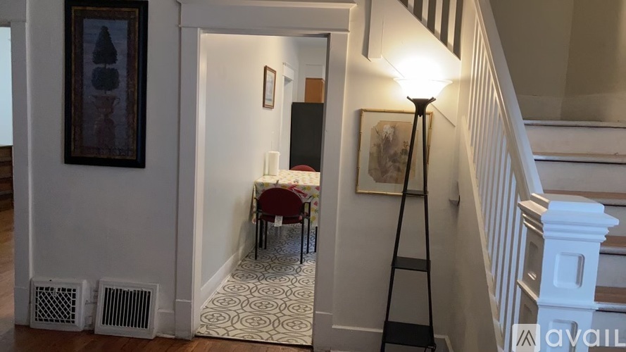 A hallway with a red chair and a painting on the wall.