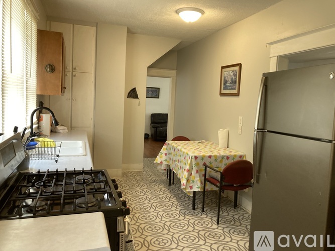 A kitchen with a black stove top and a dining table with chairs.