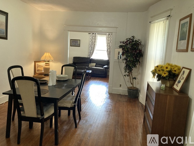 A dining room with a table set for two and a couch in the background.