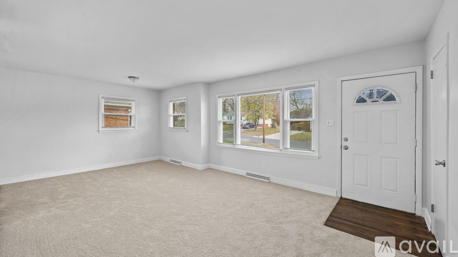 A spacious room with a white door and carpeted floor.