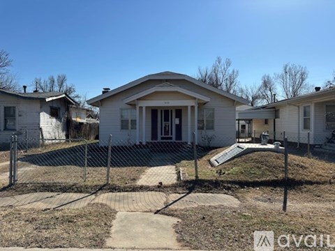 A house with a fenced front yard and a small pathway leading to the front door.