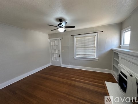 A room with a ceiling fan and wooden flooring.