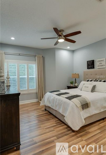 A bedroom with a bed, a dresser, and a ceiling fan.