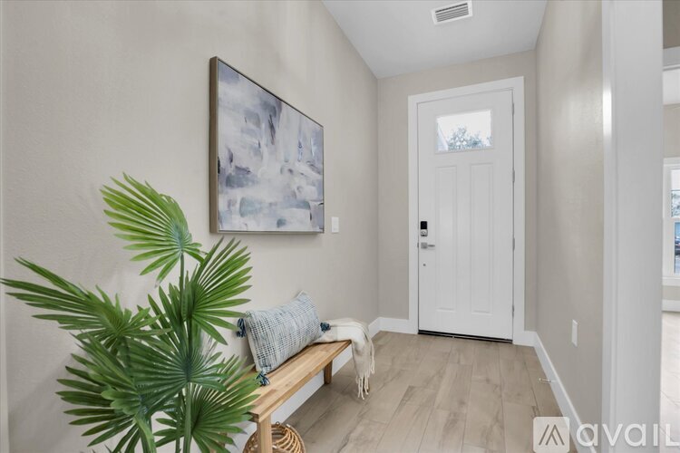 A room with a white door, a bench, and a painting on the wall.