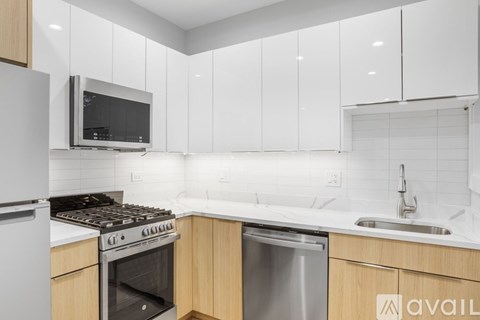 A modern kitchen with white cabinets and stainless steel appliances.