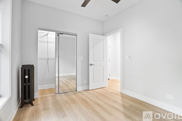 A room with a wooden floor, a white door, a glass door, and a black speaker.