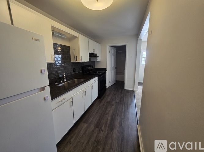 A kitchen with white cabinets and a black countertop.
