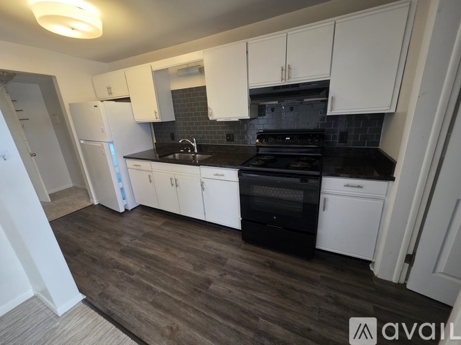 A kitchen with white cabinets and black appliances.