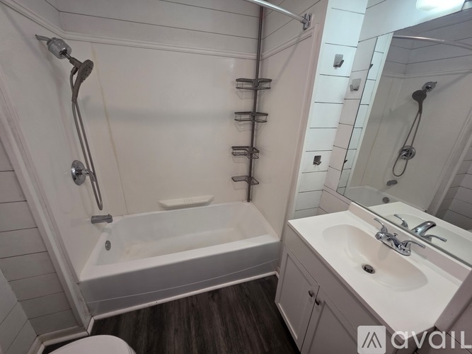 A white bathroom with a bathtub, sink, and mirror.