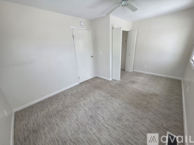 A room with a carpeted floor and a ceiling fan.