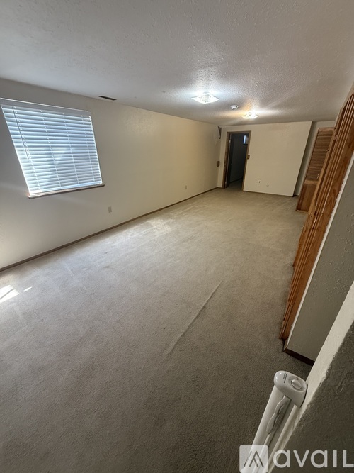 A spacious empty room with a staircase on the right side.