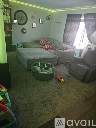 A living room with a grey couch and a green ottoman.