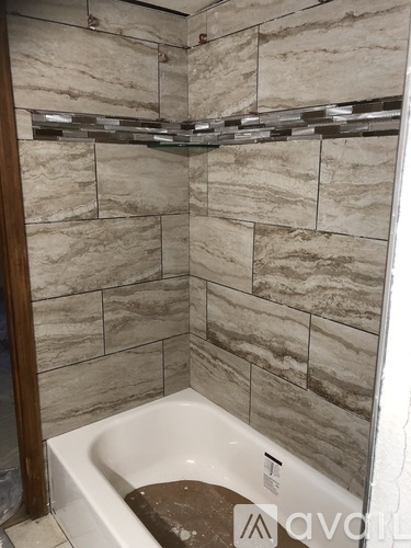 A bathroom with a tiled wall and a white bathtub.