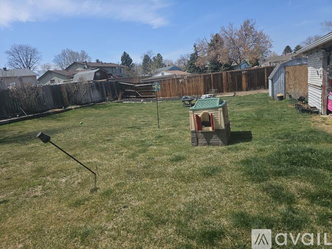 A backyard with a wooden fence and a small wooden structure in the middle of the grass.
