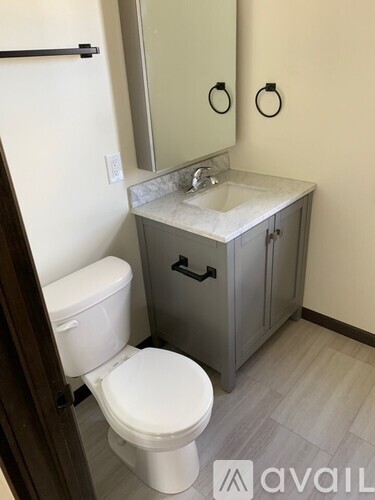 A bathroom with a toilet, sink and mirror.