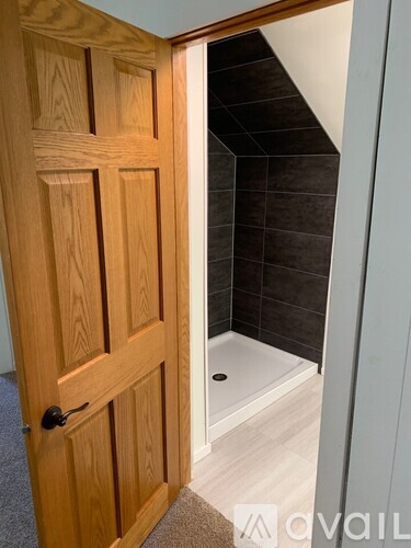 A wooden door is open to a bathroom.