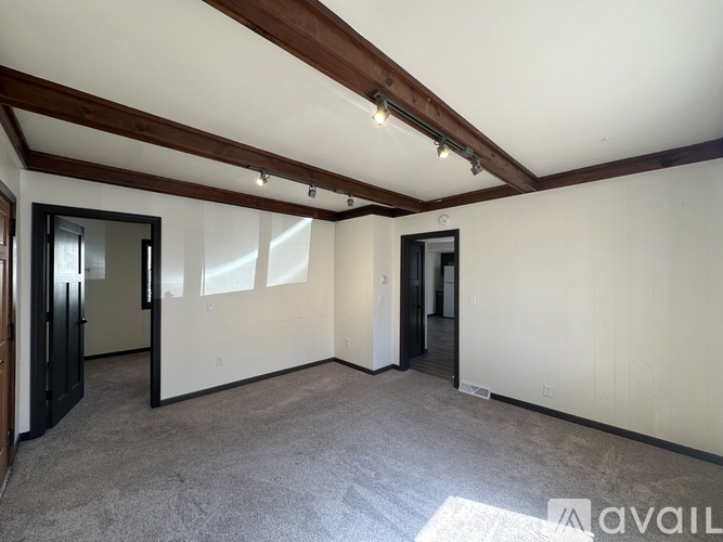 A spacious room with a wooden beam ceiling and carpeted floor.