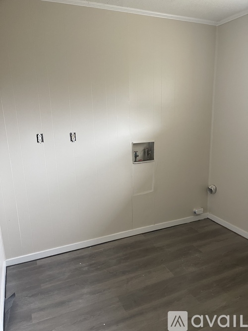 A room with a wall-mounted light switch and a wooden floor.