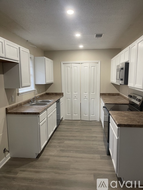A kitchen with white cabinets and a brown countertop.