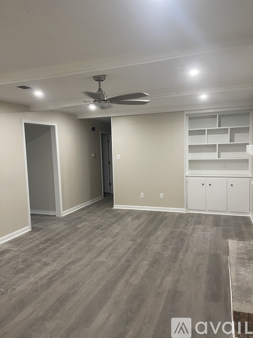 A room with a ceiling fan and grey flooring.