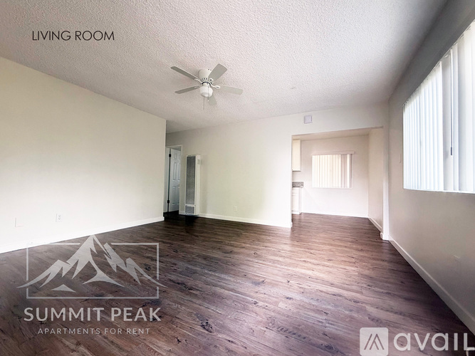 A living room with wood flooring and a ceiling fan.