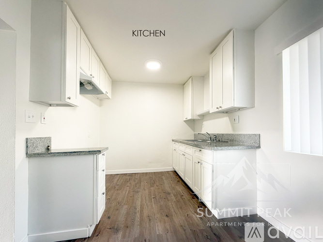 A kitchen with white cabinets and a wooden floor.