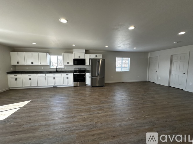 A spacious kitchen with white cabinets and a wooden floor.