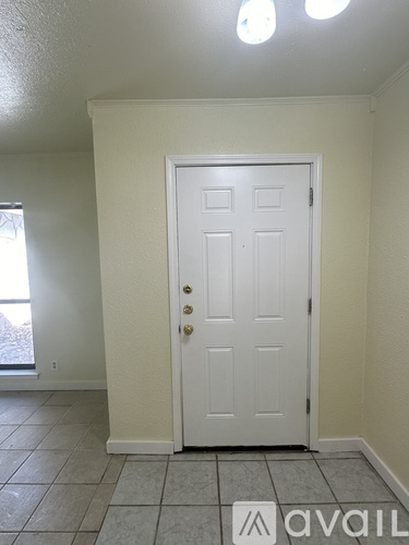 A white door with a gold handle is in a room with white walls.