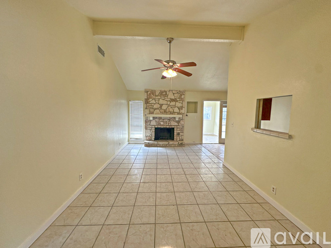 A spacious room with a fireplace and a fan.