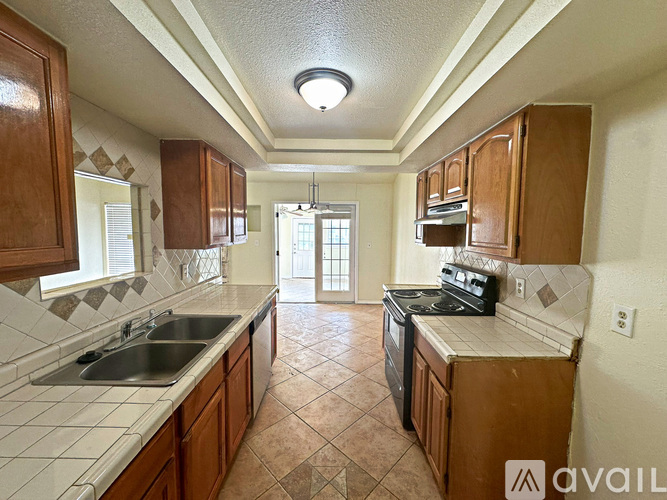 A kitchen with brown cabinets and a black stove top oven.