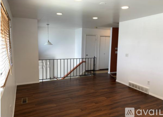 A room with wooden floors and a staircase with a metal railing.