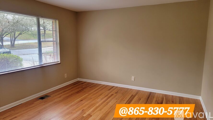 A room with a window overlooking a street and a phone number on the wall.