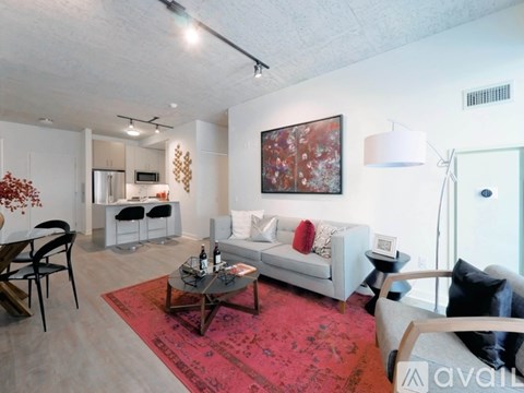 A living room with a white couch, a red rug, and a painting on the wall.