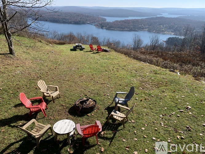 A group of chairs and tables are set up on a hillside overlooking a lake.