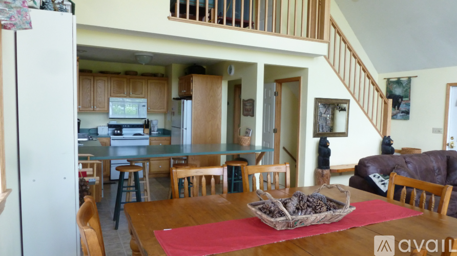 A kitchen with a refrigerator, a dining table with chairs, and a staircase.