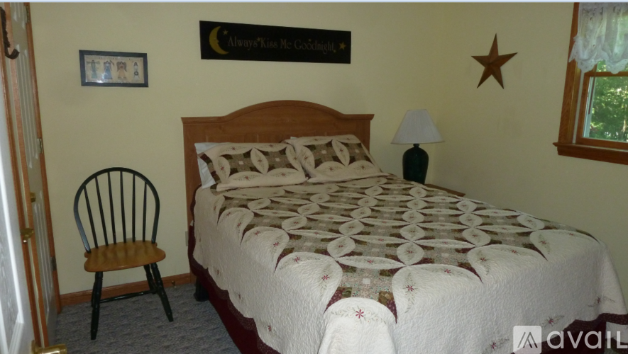 A bedroom with a bed, chair, and a star decoration on the wall.
